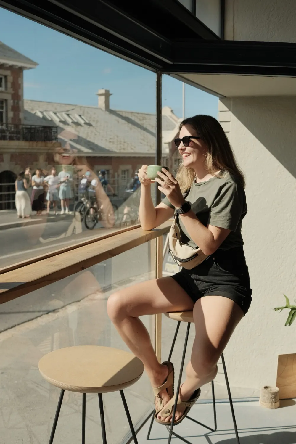 A customer on a stool at the window counter with a coffee, Muizenberg outside