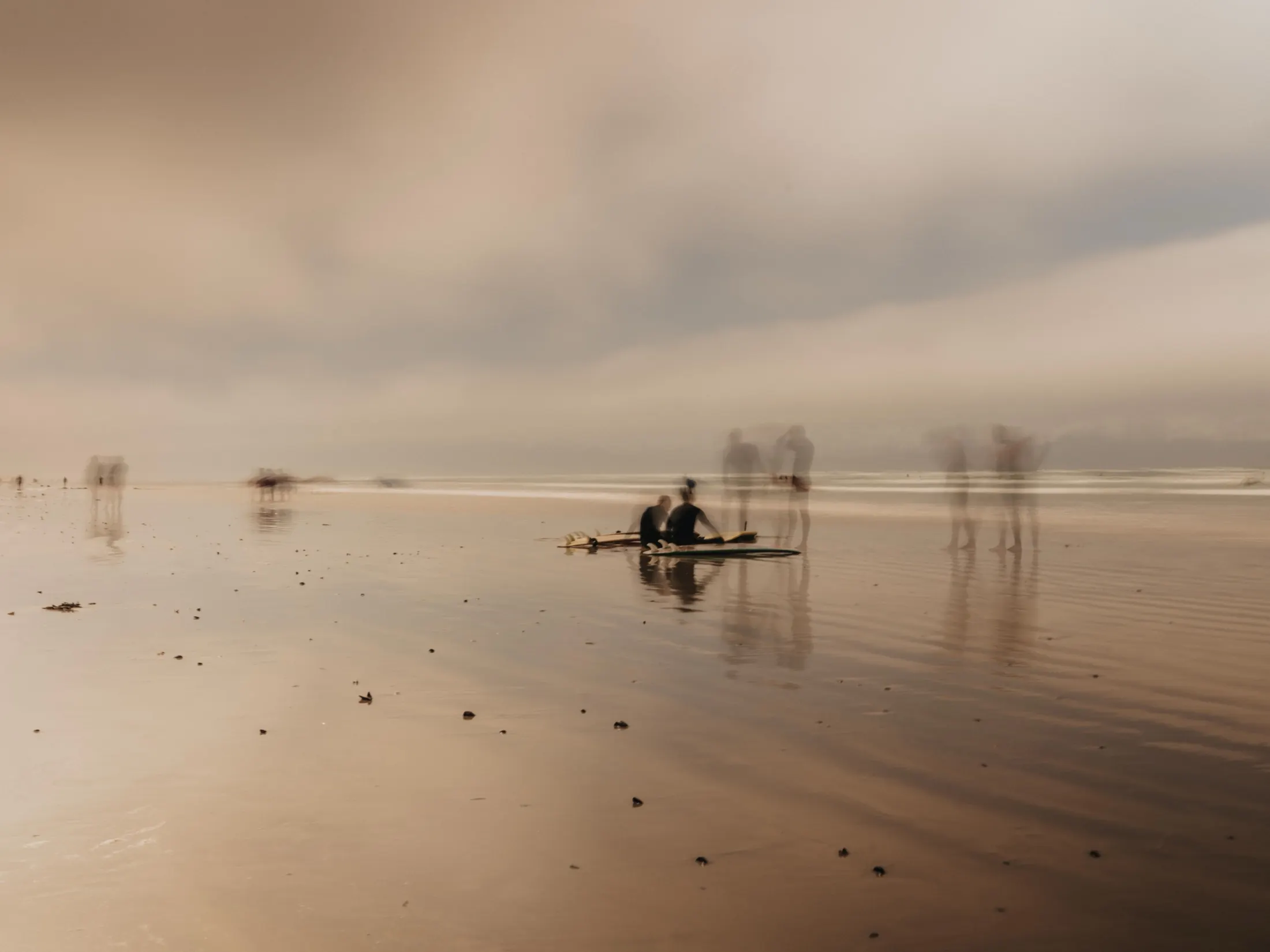 A lone paddler on a glassy, misted shorebreak at dawn