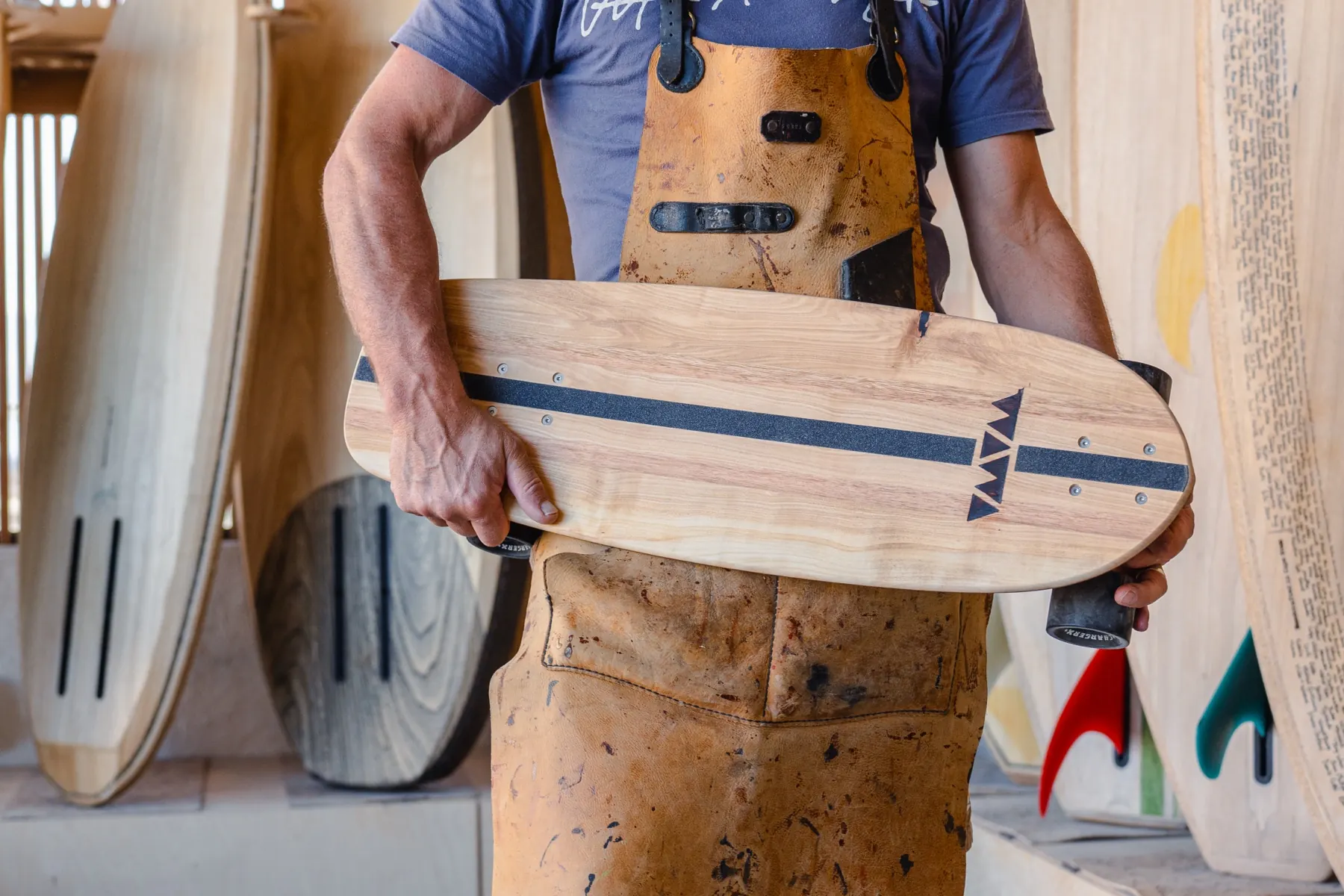 A shaper holding a finished wooden cruiser deck in the workshop