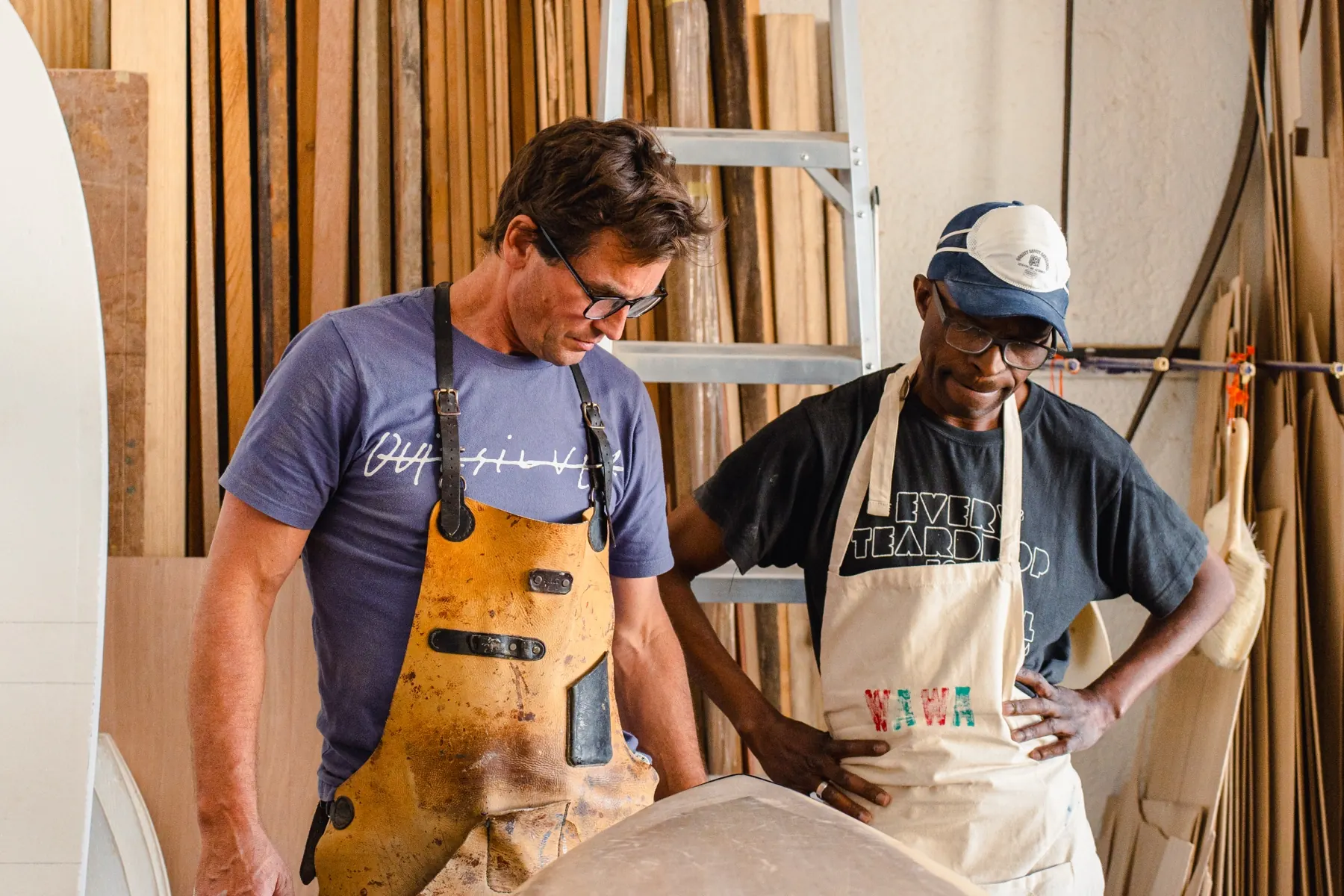 Two shapers working a board together in the Wawa workshop